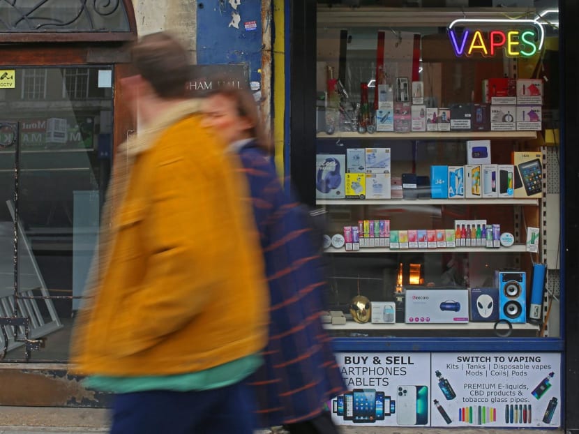 People walk past a newsagent advertising the sale of vape electronic cigarettes in Streatham Hill, South London, on April 1, 2023.