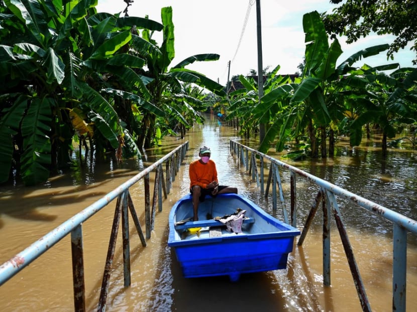 A resident steers his boat over a footbridge through a flooded neighborhood in the central Thai province of Ayutthaya on Sept 28, 2021, as tropical storm Dianmu caused flooding in 30 provinces across the country.