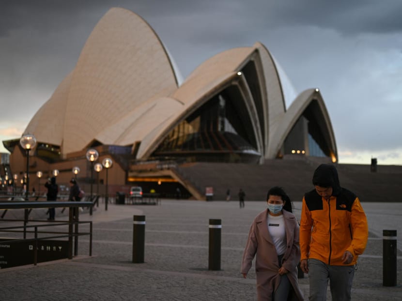People walk in front of the Sydney Opera House in Sydney amid the coronavirus.