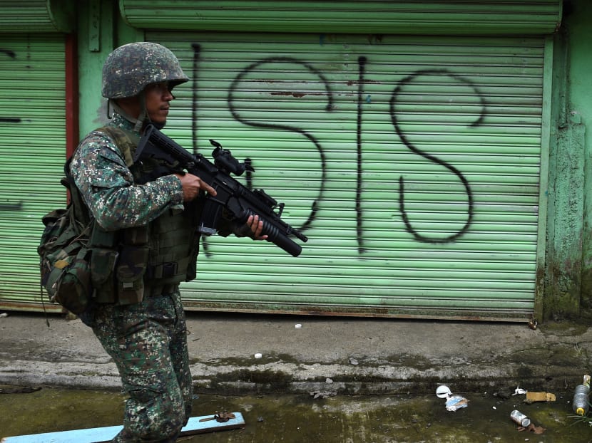 A Philippine Marine walks past graffiti during a patrol along a deserted street at the frontline in Marawi, on the southern island of Mindanao on July 22, 2017. Photo:AFP