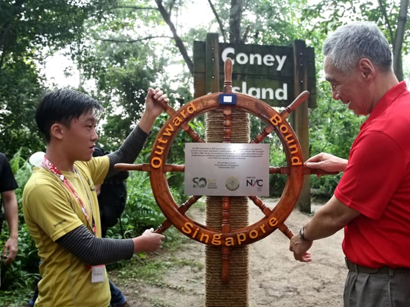PM Lee, together with Tay Jing Xun, 15, an Outward Bound Singapore participant from North Vista Secondary School, mount the OBS nautical wheel on Coney Island to symbolise the expansion of the future use of the island by OBS. Photo: Nuria Ling/TODAY