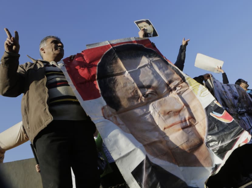 Supporters of former Egyptian President Hosni Mubarak wave by his poster as he was taken by a helicopter ambulance from Maadi Military Hospital to a court in Cairo, Egypt, Saturday, Nov. 29, 2014. Photo: AP