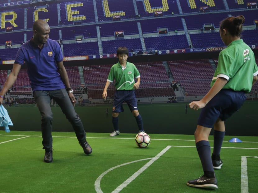 Former Barcelona star Eric Abidal playing mini-football with some youth players from the FC Barcelona Football School in Singapore during Thursday's launch of the global partnership between Nestle Milo and the Spanish club. Photo: Wee Teck Hian