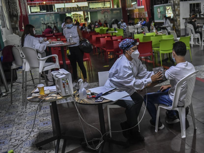 A nurse checks the pressure of a man who received the Moderna vaccine against COVID-19 at a vaccination point in the La Cantina bar in Medellin, on August 11, 2021. People over 18 years of age who work in the gastronomic sector are being vaccinated as part of a programme sponsored by the private sector.