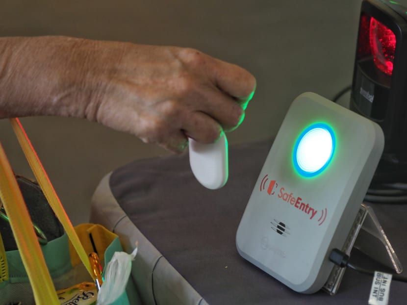 A person scanning a TraceTogether token at a SafeEntry check-in point.