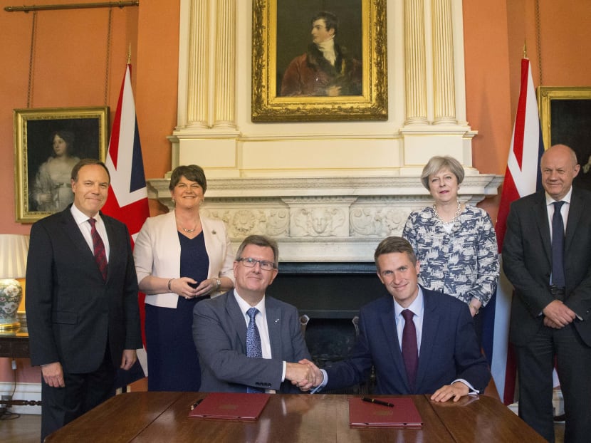 Britain's Prime Minister Theresa May (2R) stands with Britain's First Secretary of State Damian Green (R), Democratic Unionist Party (DUP) leader Arlene Foster (2L), DUP Deputy Leader Nigel Dodds (L), as DUP MP Jeffrey Donaldson (3L) shakes hands with Britain's Parliamentary Secretary to the Treasury, and Chief Whip, Gavin Williamson, inside 10 Downing Street in central London. Photo: AFP