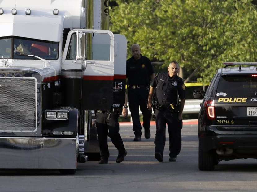 San Antonio police officers investigate the scene where eight people were found dead in a tractor-trailer loaded with at least 30 others outside a Walmart store in stifling summer heat in what police are calling a horrific human trafficking case, Sunday, July 23, 2017, in San Antonio. Photo: AP