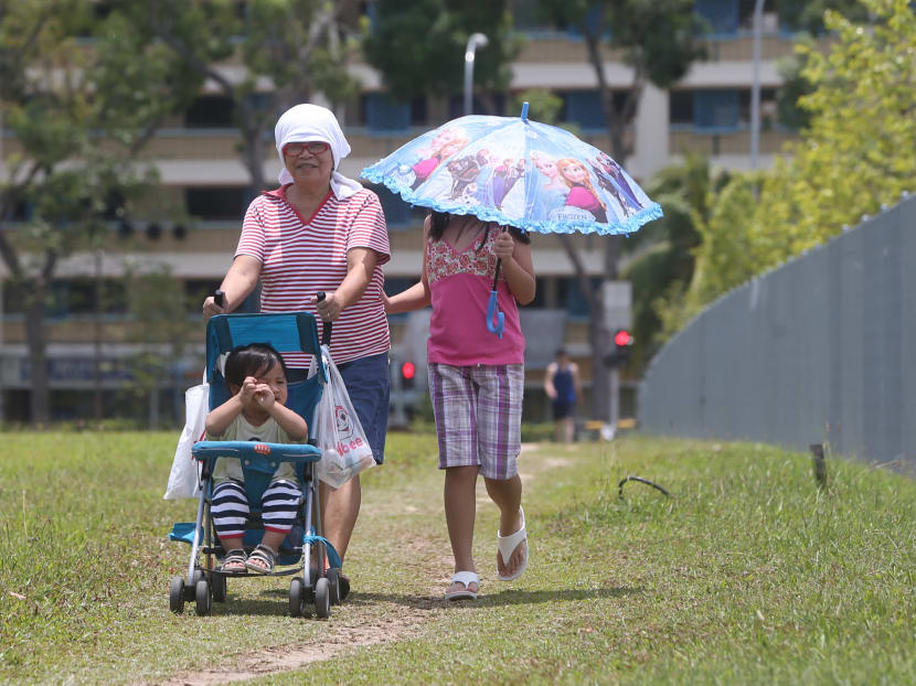 People shield themselves from the heat. Photo: Ooi Boon Keong/TODAY