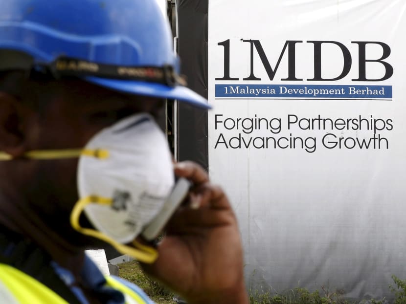 A construction worker talks on the phone in front of a 1Malaysia Development Berhad (1MDB) billboard at the Tun Razak Exchange development in Kuala Lumpur, Malaysia. Photo: Reuters
