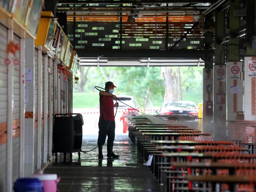 A cleaning worker washing the tables at 115 Bukit Merah View Market and Food Centre on June 14, 2021.