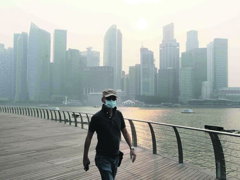A man is seen wearing a mask to protect himself from the haze as he walks along the Marina Bay Sands Waterfront Promenade at 5.30pm on Oct 6, 2014. Photo: Ooi Boon Keong