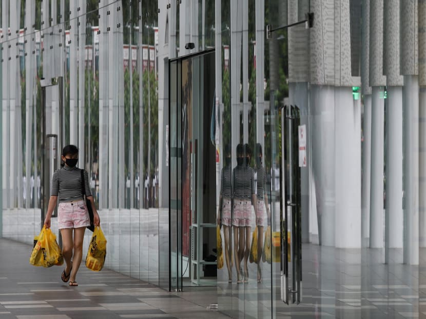 A woman wearing a protective face mask walks into a mall in Singapore.