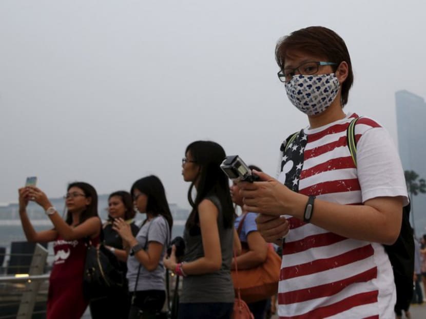 A woman wearing a mask passes the central business district shrouded by haze on Sept 10, 2015. Photo: Reuters