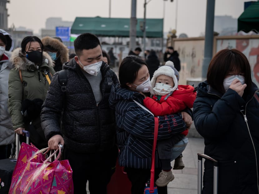 People wear protective masks to help stop the spread of the deadly new coronavirus which began in Wuhan, as they queue to take a taxi at the Beijing railway station.