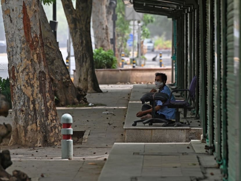 A security guard sits in front of closed shops along the roadside during a lockdown amid the Covid-19 pandemic in New Delhi on May 23, 2021.