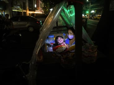 This photo taken on Aug 24, 2022 shows Ms Maricel Abawag and her son resting inside their pushcart "home" next to a residential condominium building in Quezon City, suburban Manila.