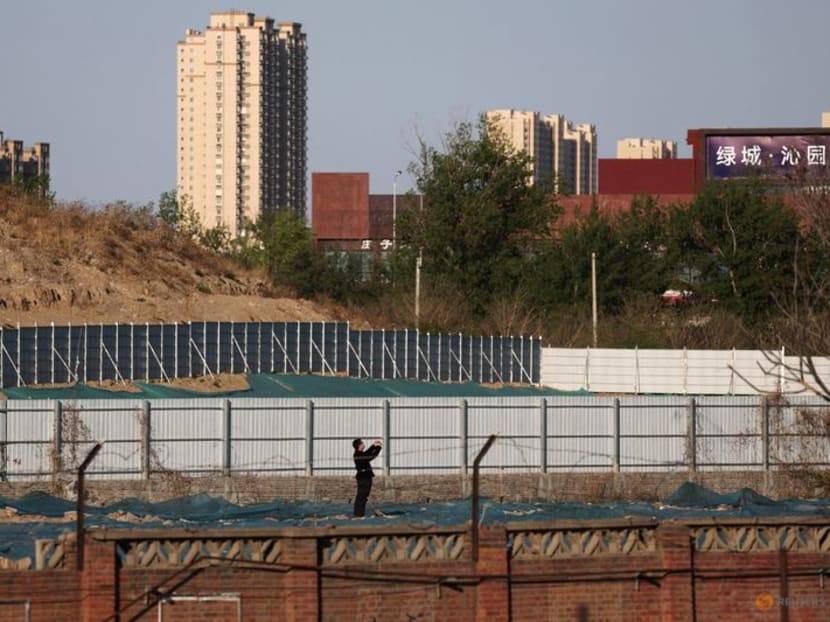 FILE PHOTO: A man walks at a construction site near residential buildings in Beijing, China April 14, 2022. REUTERS/Tingshu Wang FILE PHOTO: A man walks at a construction site near residential buildings in Beijing, China April 14, 2022. REUTERS/Tingshu Wang