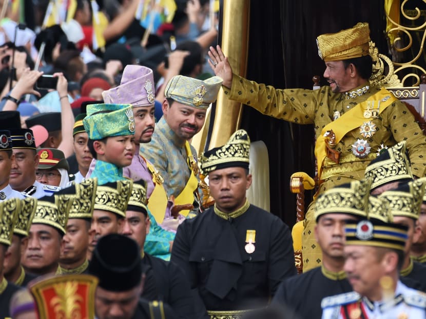 Brunei's Sultan Hassanal Bolkiah (R) waves while Crown Prince Al-Muhtadee Billah (2nd R), Prince Abdul Malik (2nd L) and Prince Abdul Wakeel (L) look on from the royal chariot during a procession to mark his golden jubilee of accession to the throne in Bandar Seri Begawan on October 5, 2017. Photo: AFP