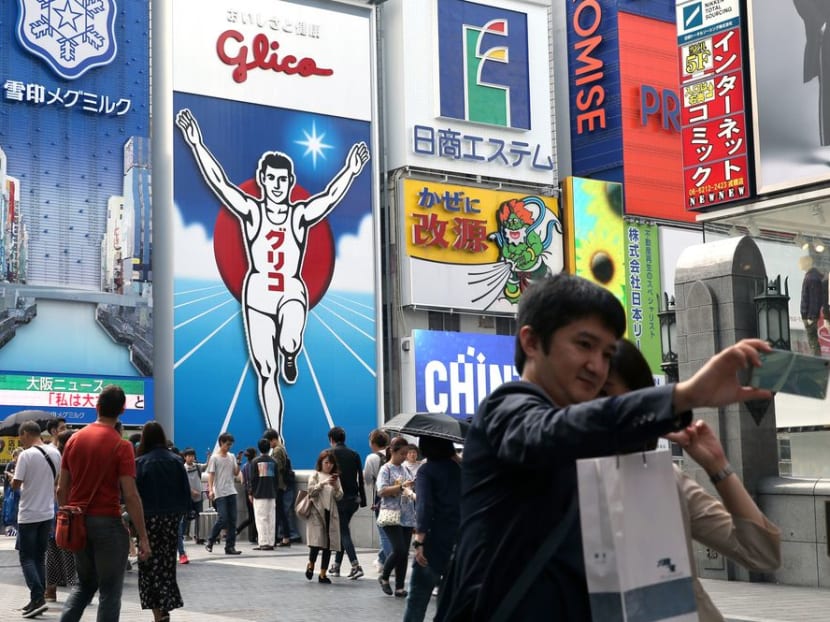 Tourists pose for a selfie in the Dotonbori district in Osaka, Japan. Photo: BLOOMBERG