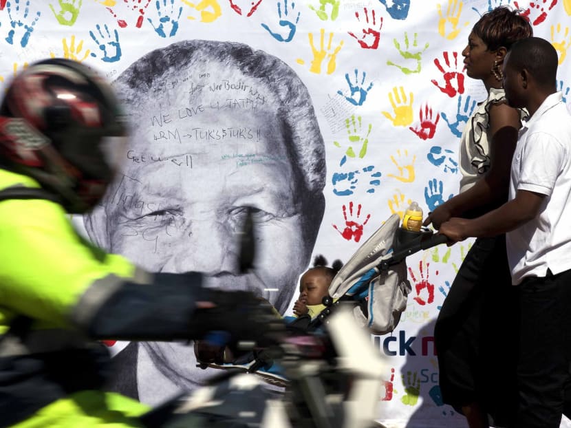 A couple walks in front of a well wisher's large banner of Nelson Mandela outside the Mediclinic Heart Hospital where former South African President Nelson Mandela is being treated in Pretoria, South Africa Friday, July 19, 2013.Photo: AP