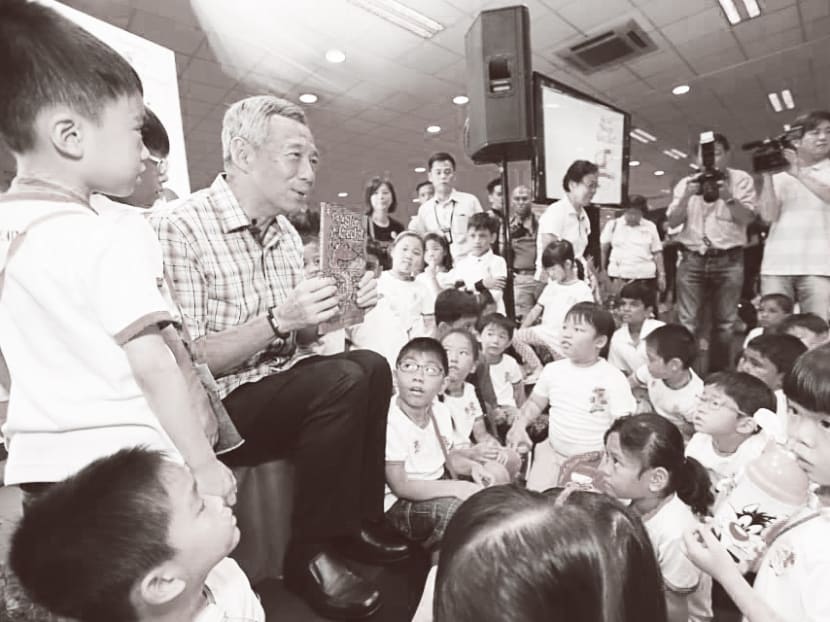 PM Lee reading Go To Sleep, Gecko! to children at the 10th anniversary of the National Library Board’s kidsREAD programme, in which volunteers read to children from low-income families. Photo: Ministry of Communications and Information
