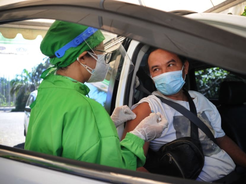 A recipient of the Covid-19 coronavirus vaccine looks on in the driver's seat of his vehicle during a drive-through vaccination service in Nusa Dua, Indonesia's resort island of Bali, on March 1, 2021.