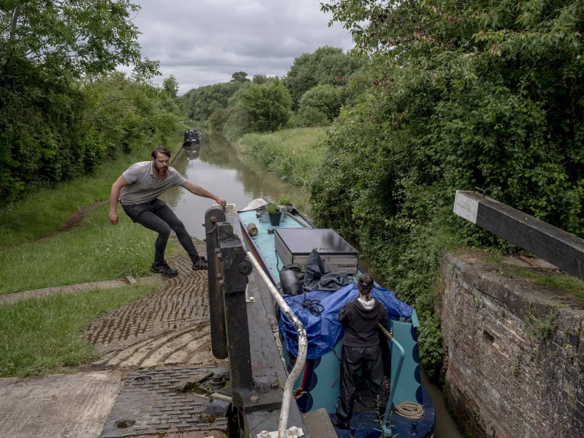A boat makes its way through a lock on the Oxford Canal near Banbury, England, on June 19, 2021. More people are calling England’s canals — and the narrow boats used to navigate them — home as remote work options in the pandemic’s wake make a mobile lifestyle more possible.