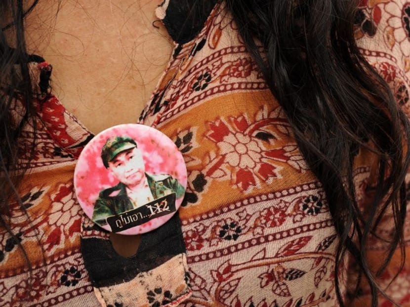 A Thai activist wears a badge carrying a picture of a lese majeste convict sentenced to 15 years in jail while calling for the repeal of article 112 of the Criminal Code, during a gathering held outside Bangkok Remand Prison. Photo: AFP