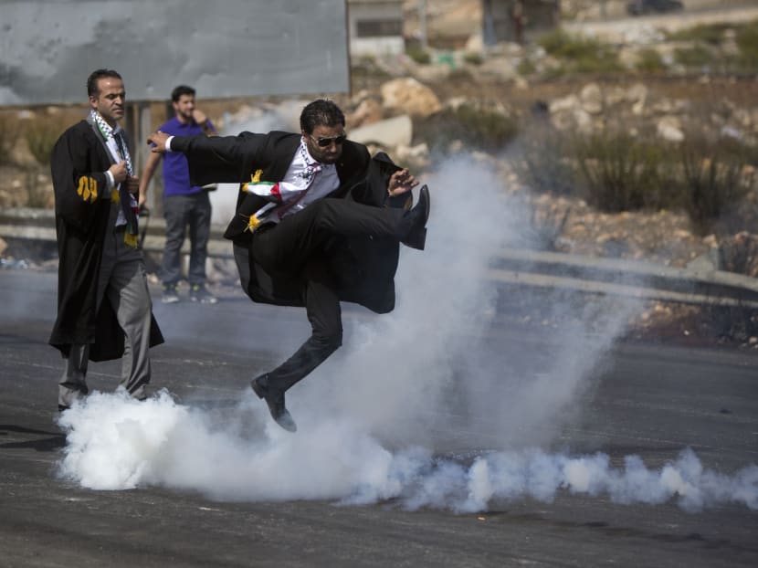 One of the most widely viewed photos of this round of Israeli-Palestinian conflict shows a Palestinian lawyer in a suit and black legal robe as he kicks away an Israeli tear gas canister, his legs flying high above a streak of white gas. Photo: AP