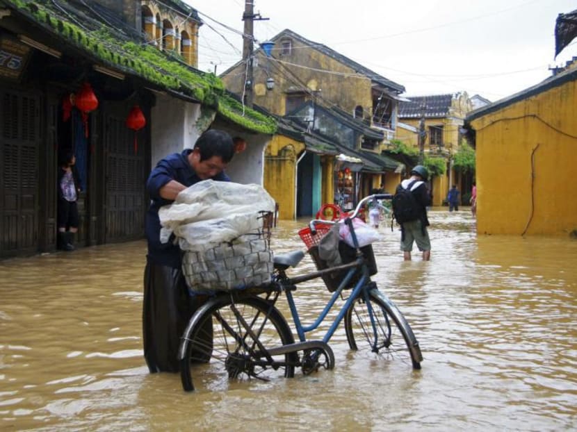 A man transporting rice cakes for sale on his bicycle, looks at his produce while standing on a flooded street in Vietnam's central ancient town of Hoi An on Nov 18, 2013. Photo: Reuters