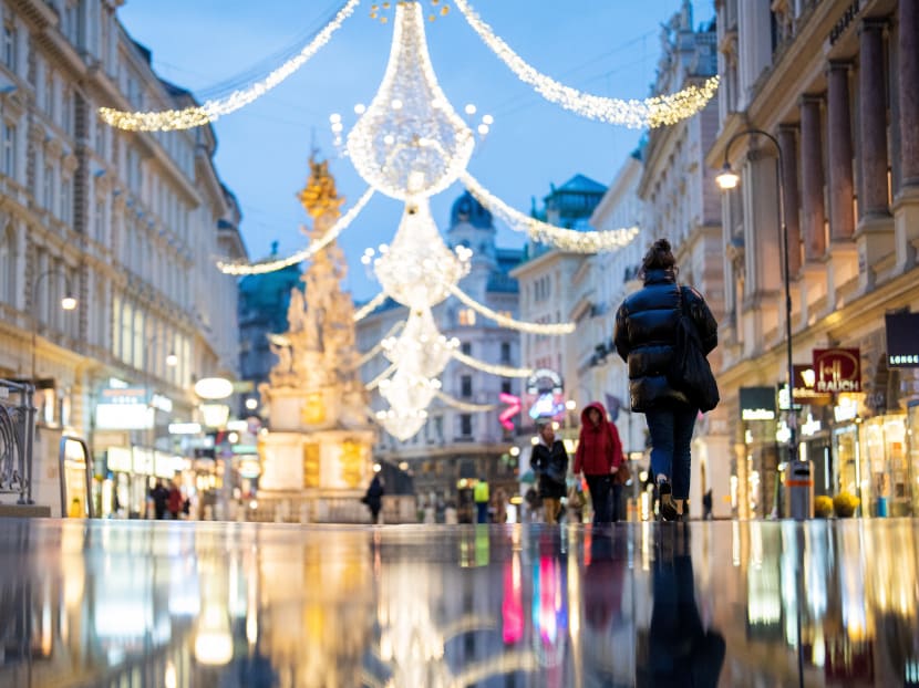 People walk down a street decorated with Christmas lights in Vienna, Austria, on Nov 22, 2021.