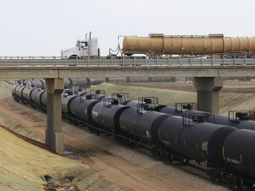 An oil tanker truck leaving an oil shipping depot as an oil train passes by in North Dakota. Analysts predict the oil industry will be the most exciting industry next year with good investment opportunities. 
Photo: THE NEW YORK TIMES