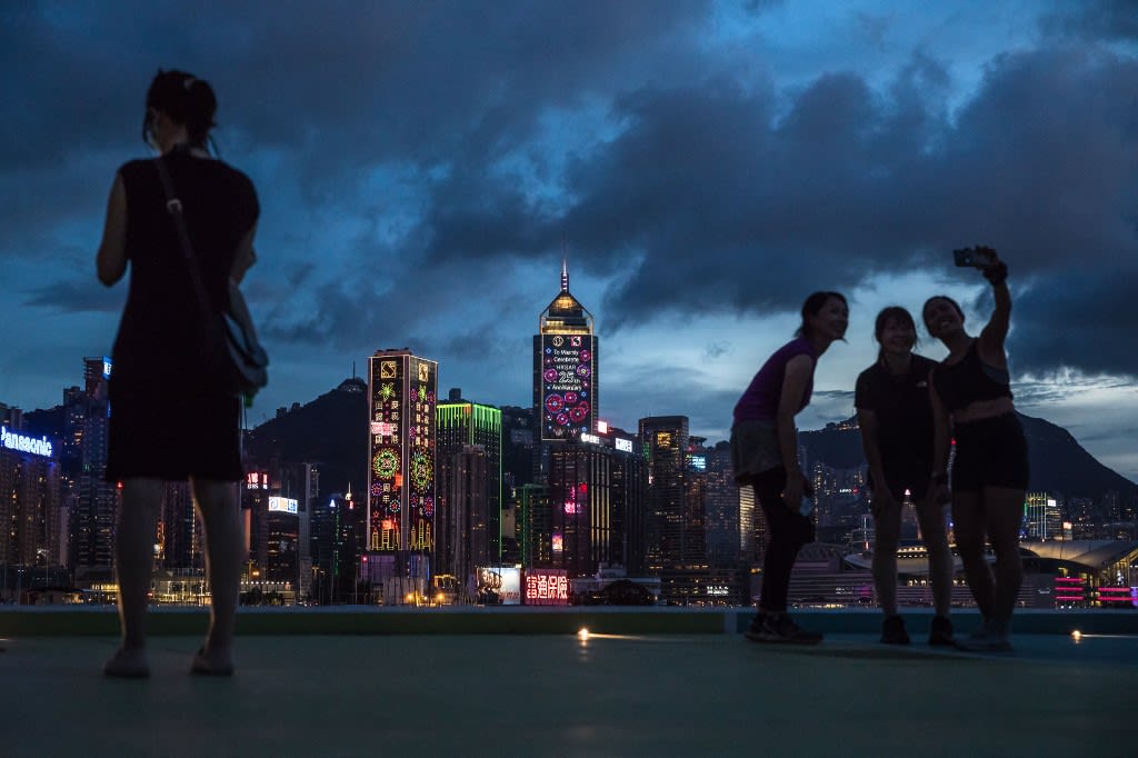 This picture taken in Hong Kong on June 29, 2022 shows buildings displaying slogans as people visit a public pier next to Victoria Harbour ahead of the 25th anniversary of the city's handover from Britain to China which falls on July 1.