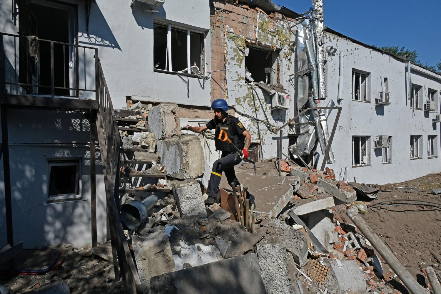 A Ukrainian deminer climb debris near the damaged building of a clinical medical laboratory following a Russian rocket strike in the second largest Ukrainian city of Kharkiv on Aug 9, 2022.