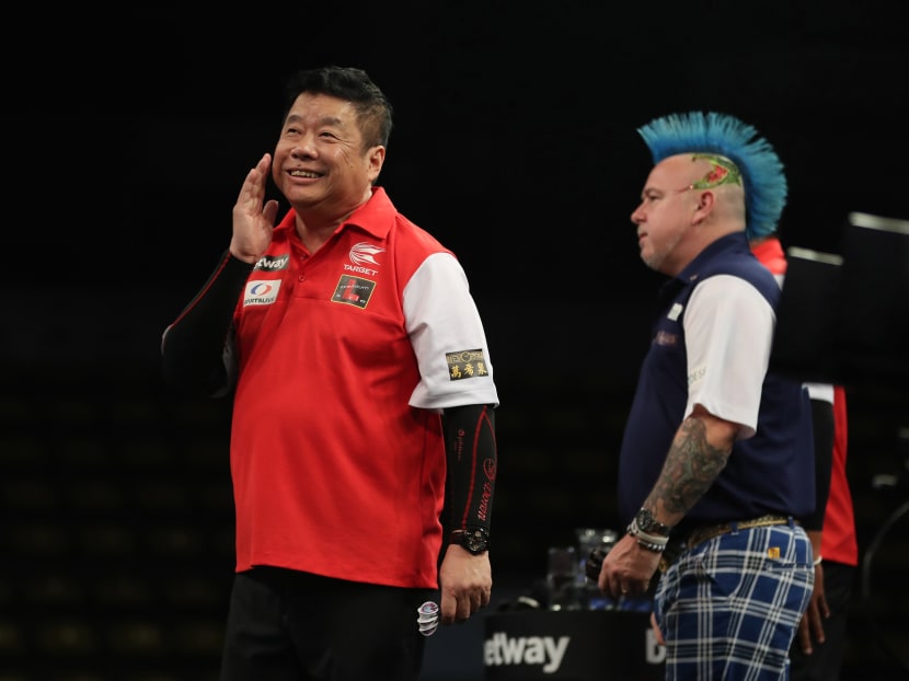 Paul Lim smiles as Scotland’s Peter Wright looks away during Singapore’s battle against top seeds Scotland in the first round of the Professional Darts Corporation World Cup of Darts tournament earlier in June. Photo: Lawrence Lustig/PDC