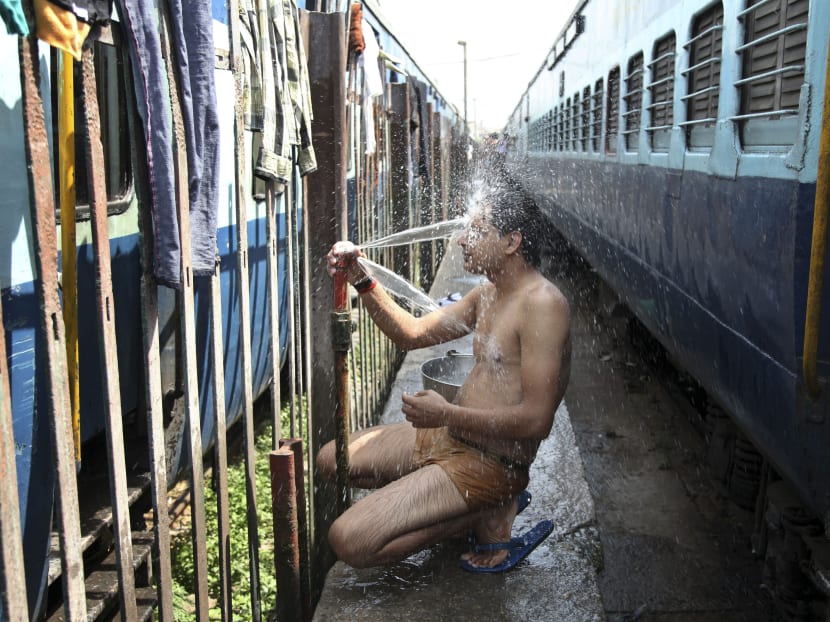 An Indian passenger takes a bath beside rail tracks on a hot summer day at a railway station in Jammu. Photo: AP