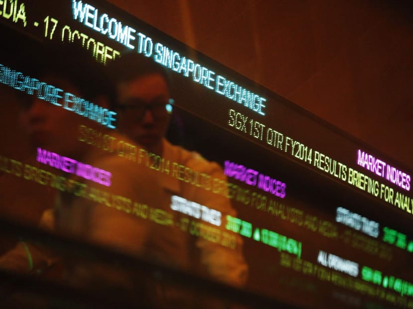 People pass stock index tickers at the Singapore Exchange (SGX) premises on Oct 17, 2013. Photo: Reuters