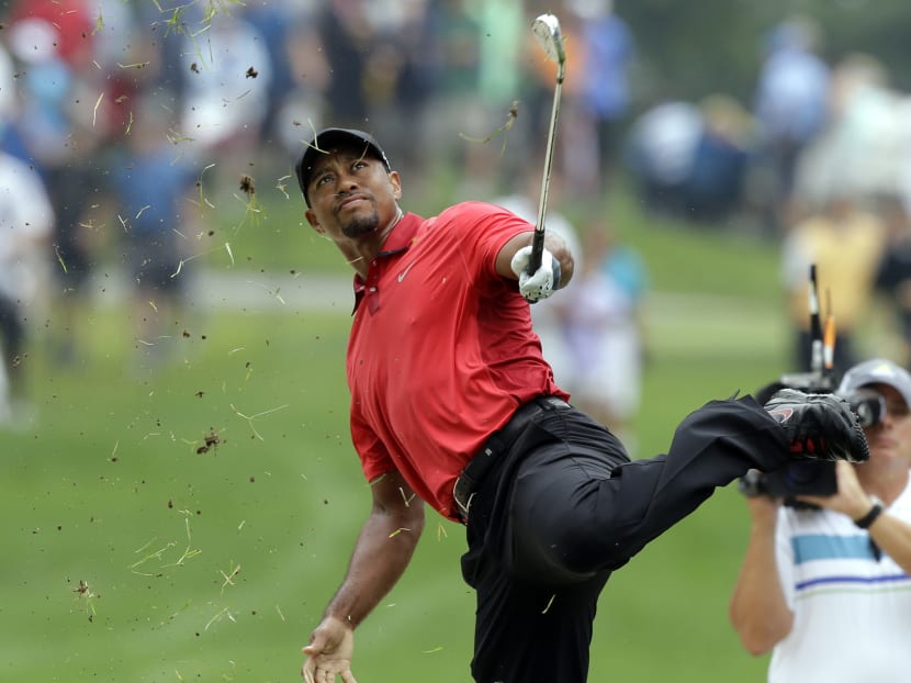 Woods playing the ‘one-footed’ shot that led to his toppling into the sand on 
the second hole at the final round of the Bridgestone Invitational on Sunday. Photo: AP