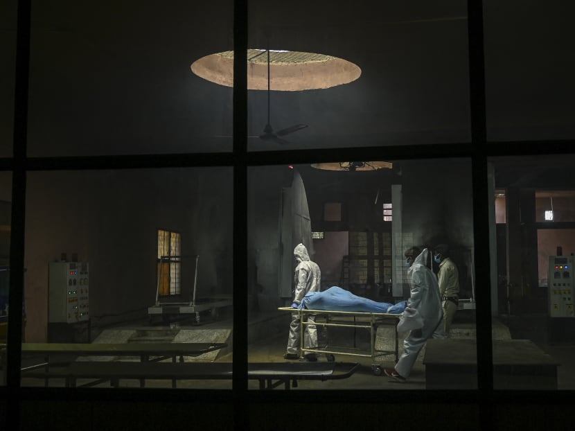 Ambulance staff wearing personal protective equipment suits carry the dead body of a person who died due to Covid-19 inside a crematorium in New Delhi, India on May 21, 2021.