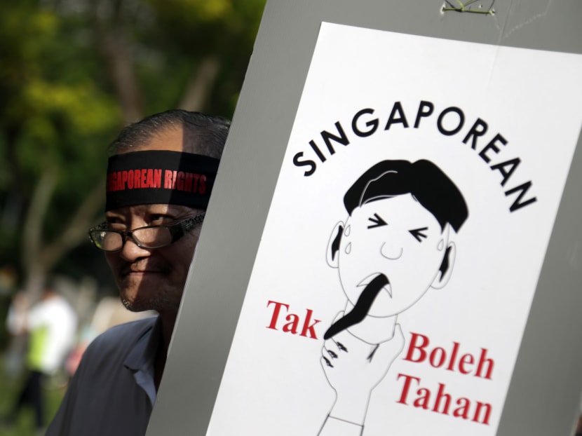 A man carries a poster which translates from the Malay language to English as "Singaporean can't take it!" as he gathers at a protest, on May 1, 2014 in Singapore to call for tighter curbs on the influx of foreigners into the city state. Photo: AP