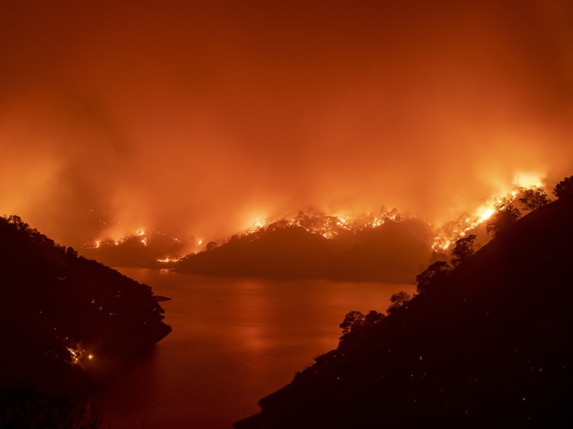 Flames surround Lake Berryessa during the LNU Lightning Complex fire in Napa, California on Aug 19, 2020. Thousands of people fled their homes in northern California on Aug 19 as hundreds of fast-moving wildfires spread across the region, burning houses and leading to the death of a helicopter pilot.