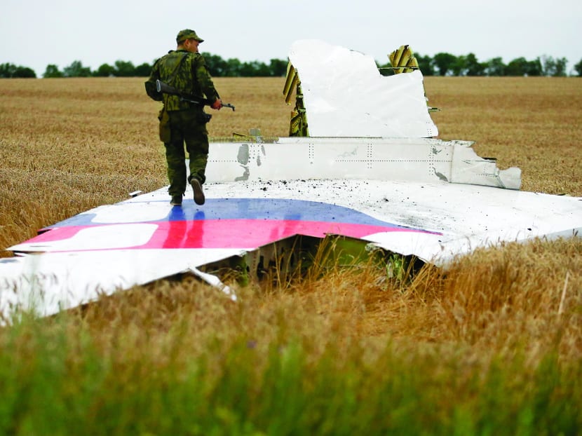 A pro-Russian separatist standing on part of the wreckage of the Malaysia Airlines Boeing 777 after it crashed in eastern Ukraine on Thursday. Photo: Reuters
