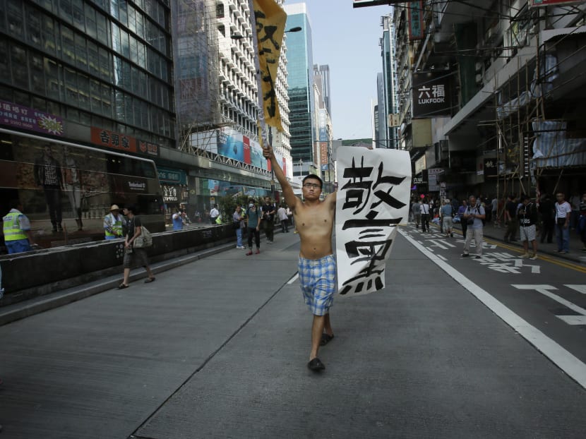 A pro-democracy protester carries a banner that reads "bad police" down an occupied section of the Mong Kok district in Hong Kong, Friday, Oct 17, 2014. Photo: AP