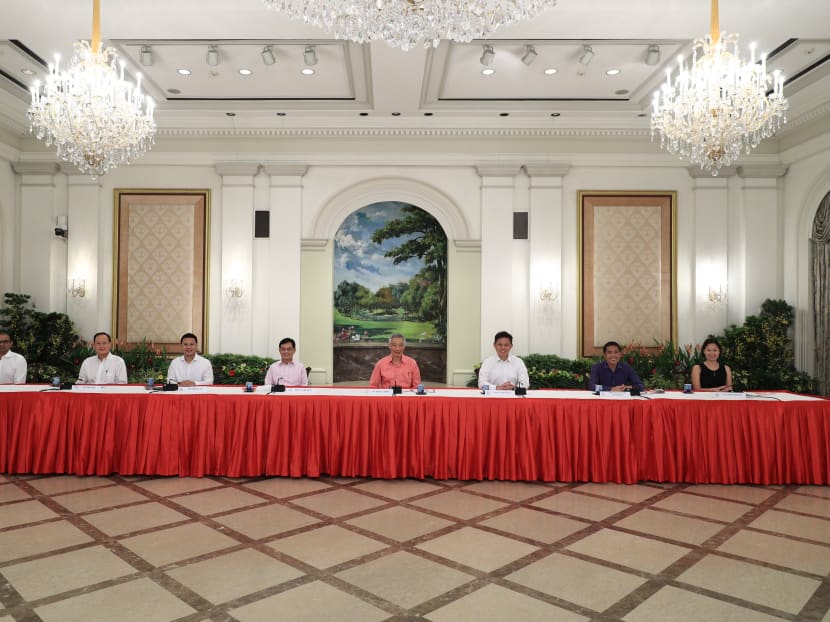 Prime Minister Lee Hsien Loong, flanked by seven political office holders, during a briefing on Saturday (July 25) to unveil the latest Cabinet line-up.