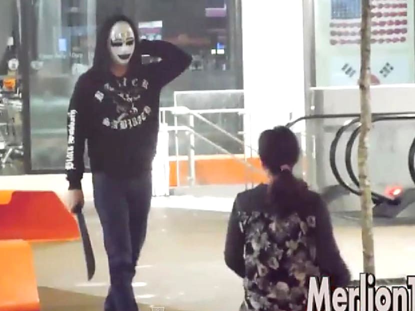 Screen grab from the video by YouTube user MerlionTV, showing a knife-wielding masked man startling a woman.