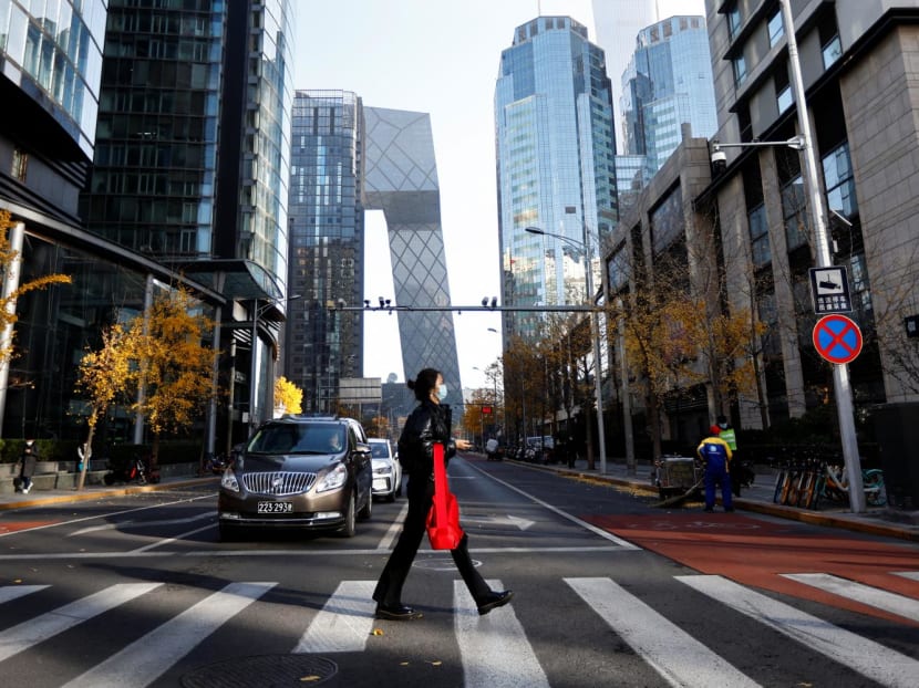 A woman walks across the street during morning rush hour, following the outbreak of Covid-19 in the Central Business District in Chaoyang District, Beijing, China on Nov 21, 2022. 
