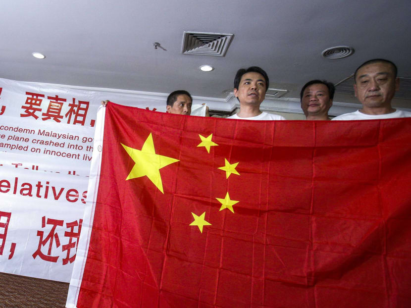 Chinese relatives of passengers onboard the missing Malaysia Airlines flight MH370 hold banners and China's national flag during a news conference at The Holiday Villa in Subang Jaya. Photo: REUTERS