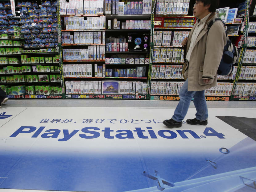 In this Dec 25, 2014 photo, a shopper walks on the logo of Sony's PlayStation 4 at an electronics store in Tokyo. Photo: AP