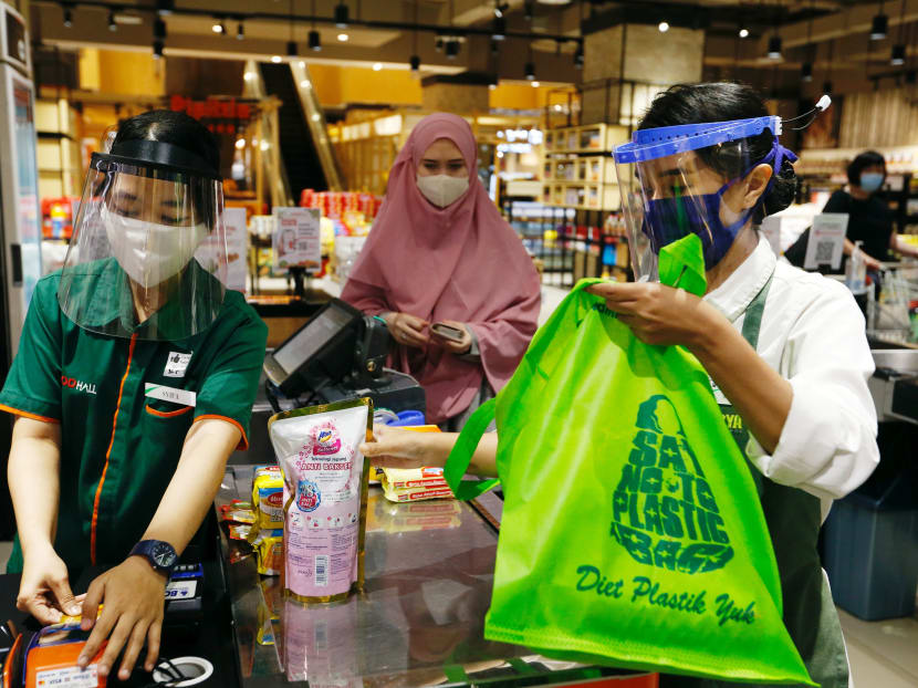 A worker uses a tote bag to replace plastic at a Jakarta supermarket on July 2, 2020, after the Indonesian government banned plastic bags from stores and markets.
