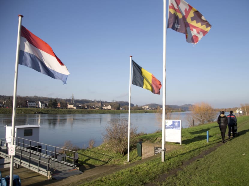 In this photo taken on Monday, Dec. 14, 2015, people walk past Dutch and Belgian flags on the waterfront in Eijsden, Netherlands. The town of Eijsden, in the Netherlands, has a short ferry which crosses the water to Lanaye, Belgium in a matter of minutes. Photo: AP